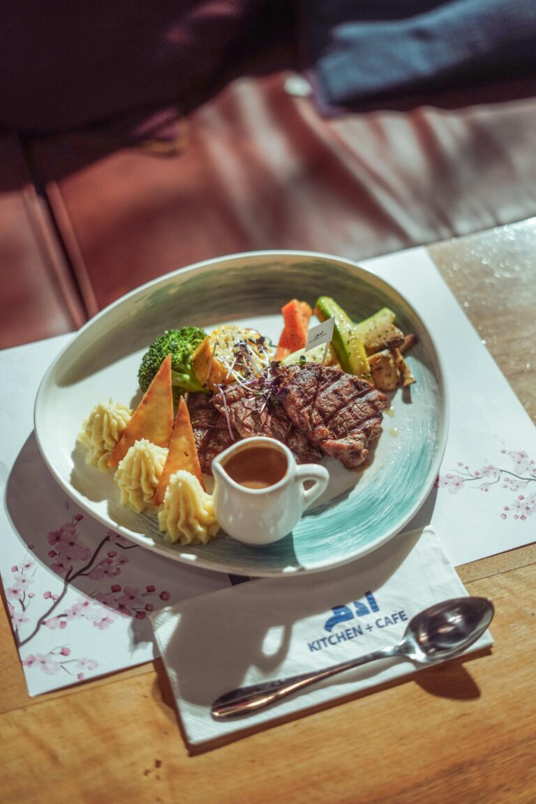 A gourmet steak dinner served elegantly with vegetables and sauce at a cafe in Baghdad.