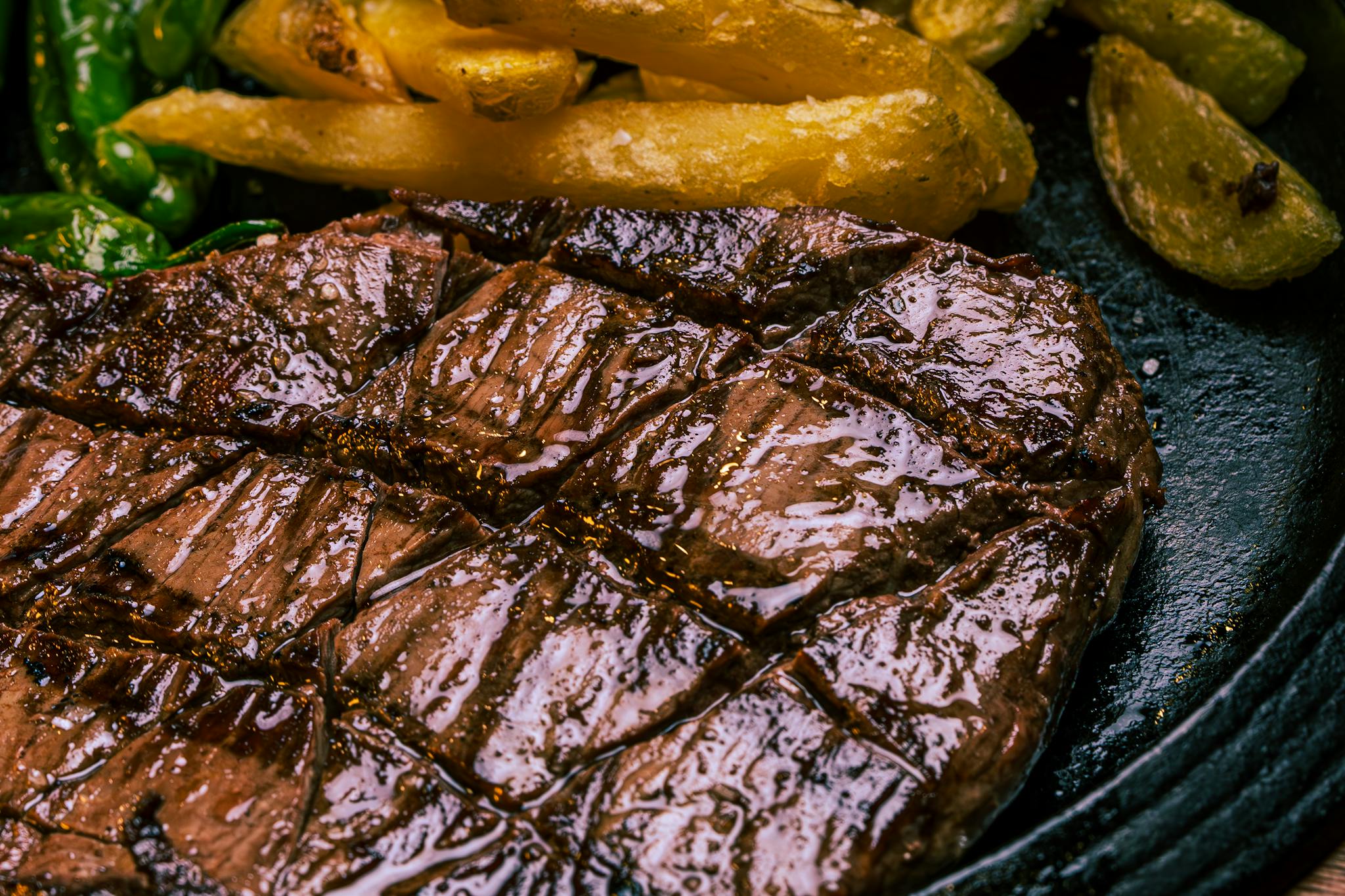 Close-up of a juicy grilled steak with crispy potatoes and vegetables, perfect dinner choice.